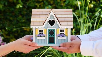 female hands and male hands holding a model house outdoors