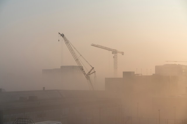 Two construction Cranes from a far in fog
